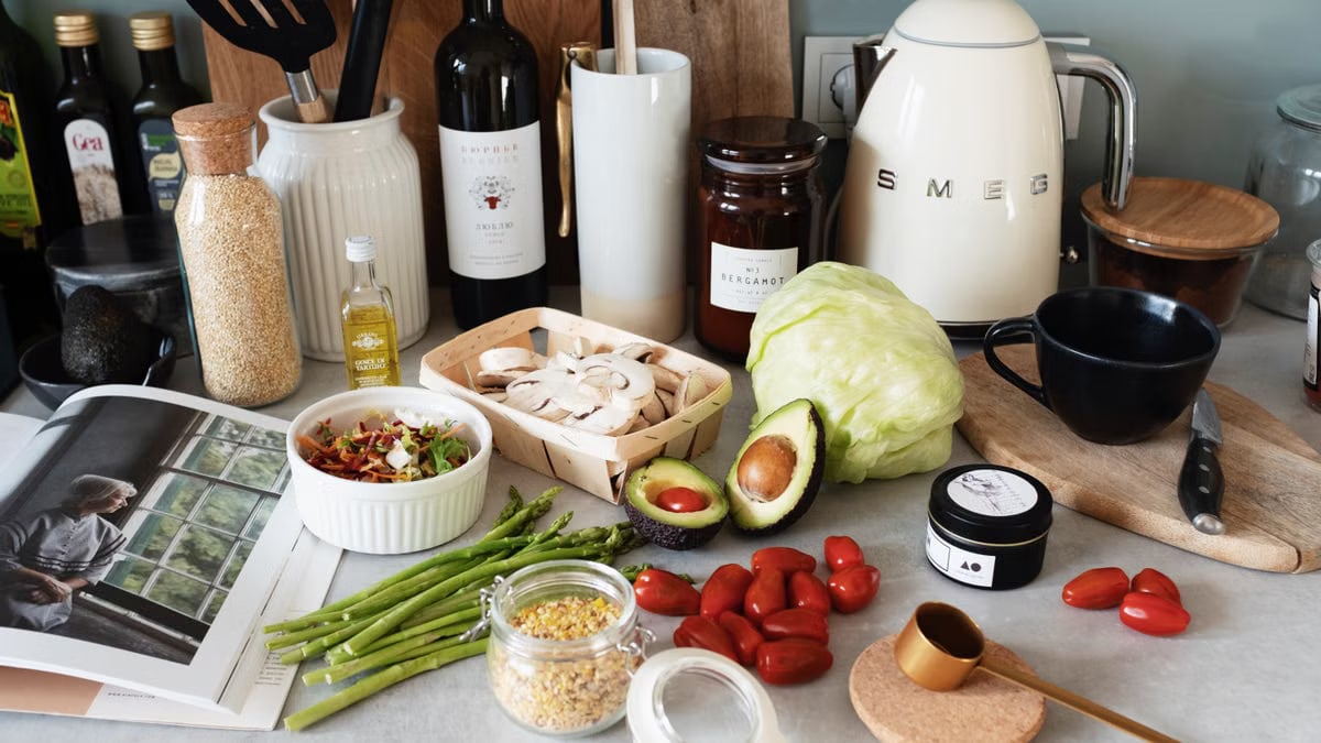 Assorted healthy food and vegetables set locating on gray countertop next to various utensils and appliances during cooking in stylish kitchen