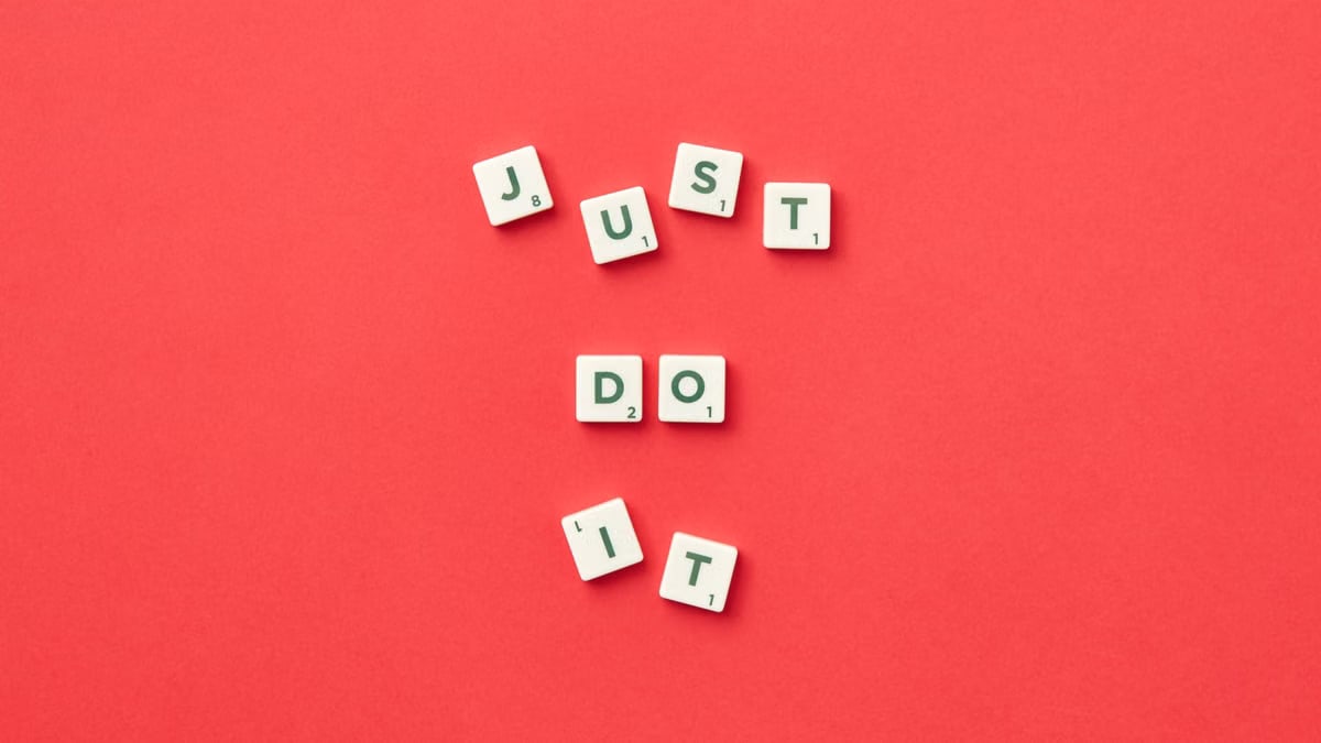 Motivational phrase 'Just Do It' spelled with Scrabble letters on a red background.